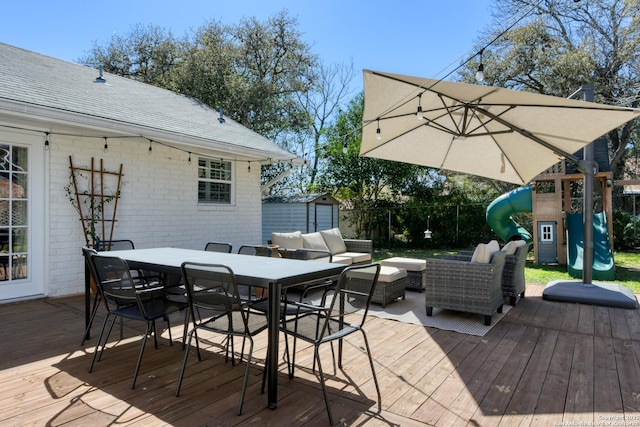 wooden terrace featuring a playground, outdoor lounge area, outdoor dining space, a shed, and an outdoor structure