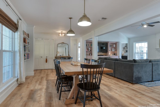 dining area with visible vents, ornamental molding, vaulted ceiling, light wood-style floors, and built in shelves