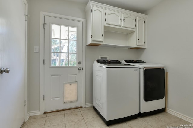 laundry room featuring washing machine and dryer, cabinet space, baseboards, and light tile patterned floors