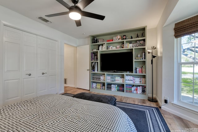 bedroom featuring a ceiling fan, a closet, visible vents, and wood finished floors