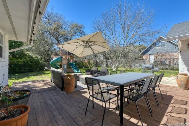 deck featuring a yard, outdoor dining area, a fenced backyard, and a playground