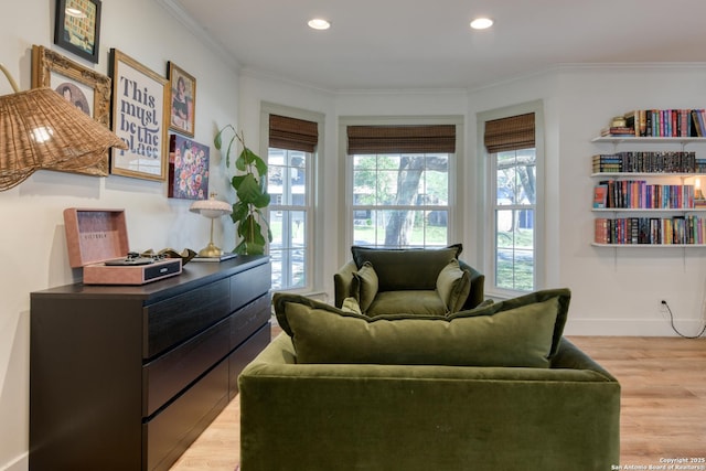 sitting room with ornamental molding, light wood-type flooring, and a wealth of natural light