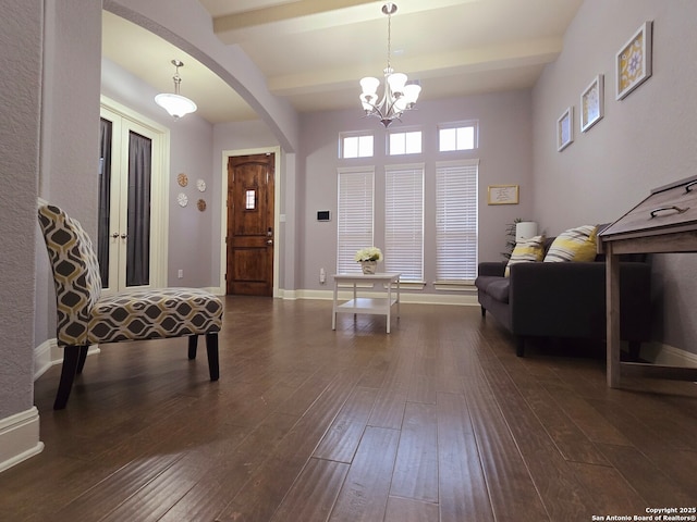 foyer entrance with an inviting chandelier, beam ceiling, and dark wood-type flooring