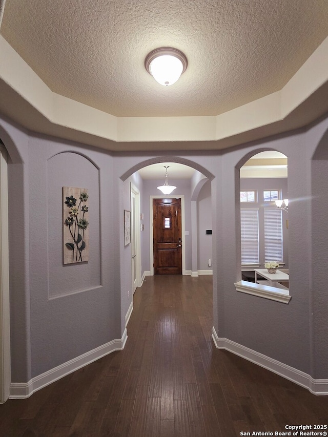 hallway with dark wood-type flooring and a textured ceiling