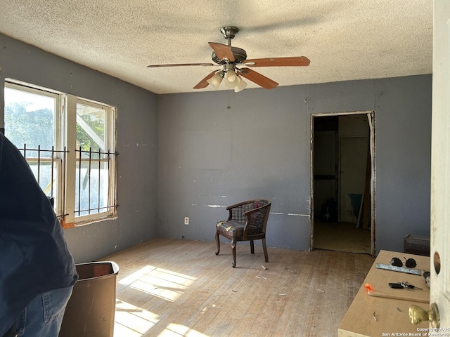 sitting room with ceiling fan, a textured ceiling, and light hardwood / wood-style floors