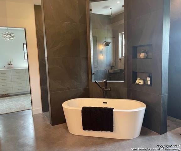 bathroom featuring vanity, concrete flooring, tile walls, and a washtub