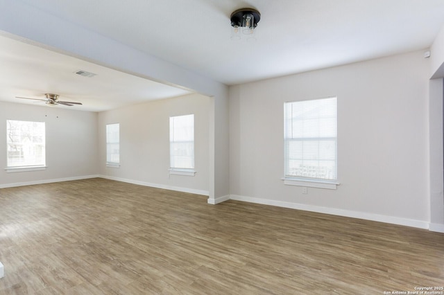 empty room with a healthy amount of sunlight, hardwood / wood-style floors, and ceiling fan