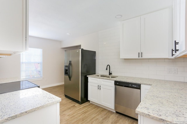 kitchen with sink, light hardwood / wood-style flooring, appliances with stainless steel finishes, decorative backsplash, and white cabinets