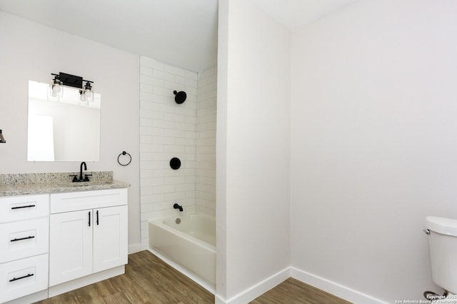 full bathroom with vanity, hardwood / wood-style flooring, toilet, and tiled shower / bath combo