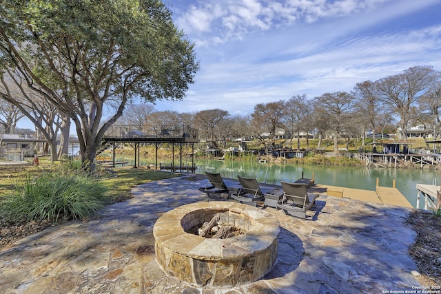 view of patio with a fire pit, a dock, and a water view