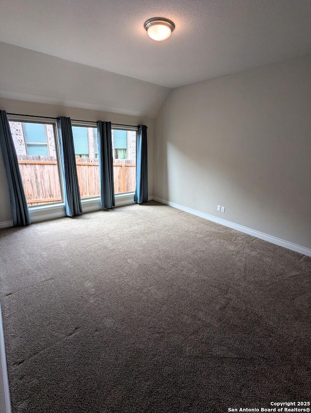 carpeted spare room featuring lofted ceiling