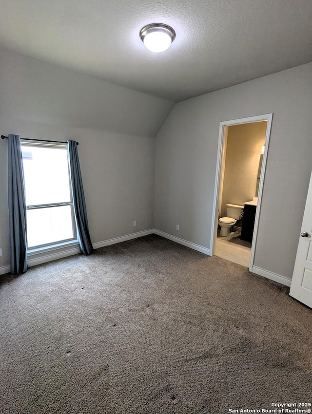 interior space with vaulted ceiling, carpet, and a textured ceiling