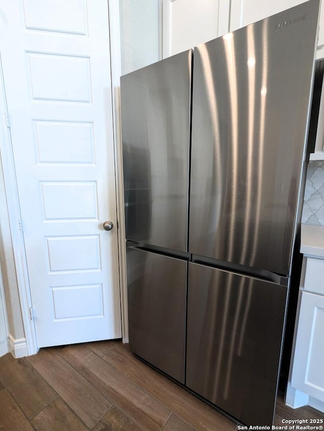 details featuring stainless steel refrigerator, dark hardwood / wood-style flooring, decorative backsplash, and white cabinets