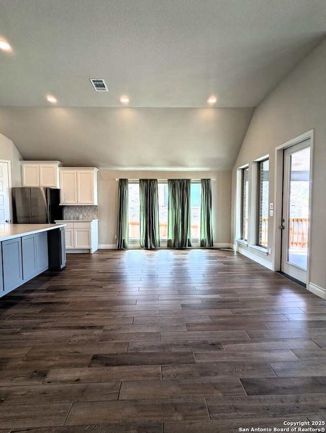 kitchen featuring white cabinetry, lofted ceiling, black refrigerator, and backsplash