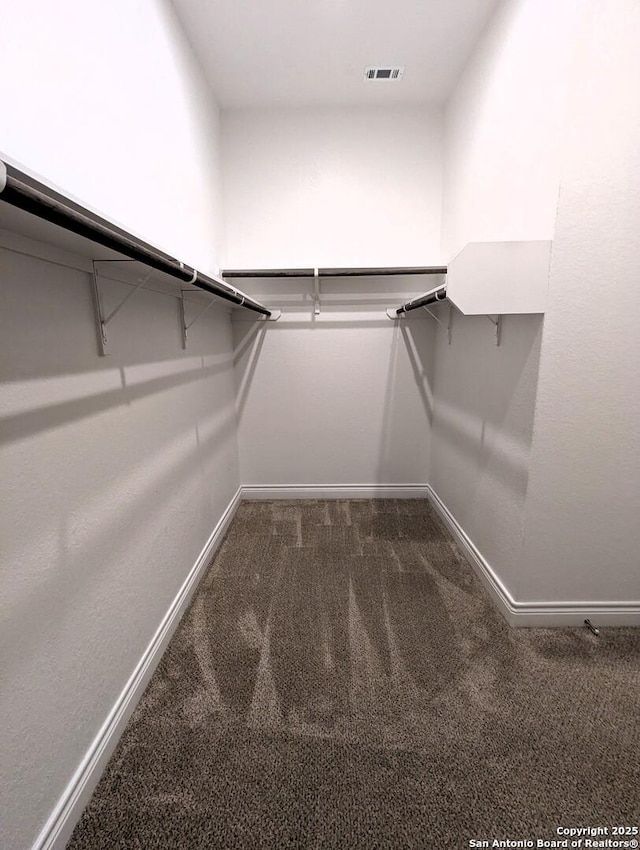 walk in closet with dark carpet