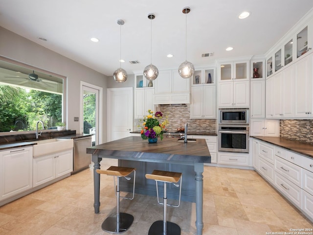 kitchen featuring pendant lighting, tasteful backsplash, white cabinets, and appliances with stainless steel finishes