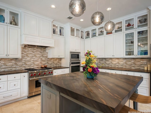 kitchen with pendant lighting, stainless steel appliances, tasteful backsplash, and white cabinets