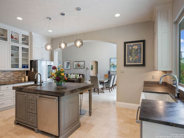 kitchen featuring stainless steel refrigerator, butcher block countertops, white cabinetry, sink, and a kitchen island with sink