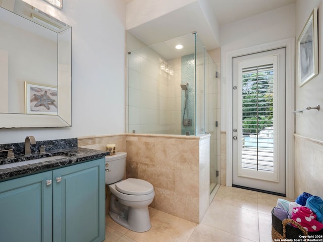 bathroom featuring tile patterned floors, vanity, toilet, and a shower with door