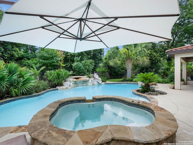 view of swimming pool featuring a patio and an in ground hot tub