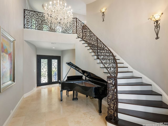 foyer with a high ceiling, an inviting chandelier, and french doors