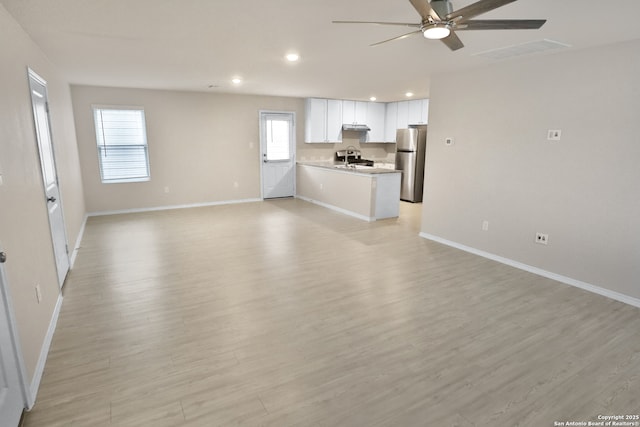 unfurnished living room featuring ceiling fan and light hardwood / wood-style floors