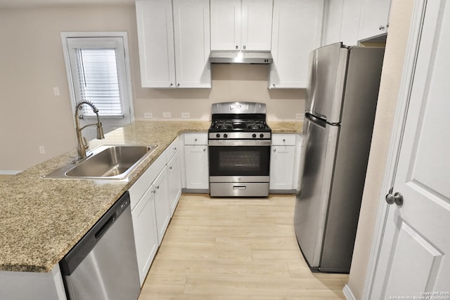 kitchen featuring appliances with stainless steel finishes, white cabinetry, sink, light stone counters, and light wood-type flooring