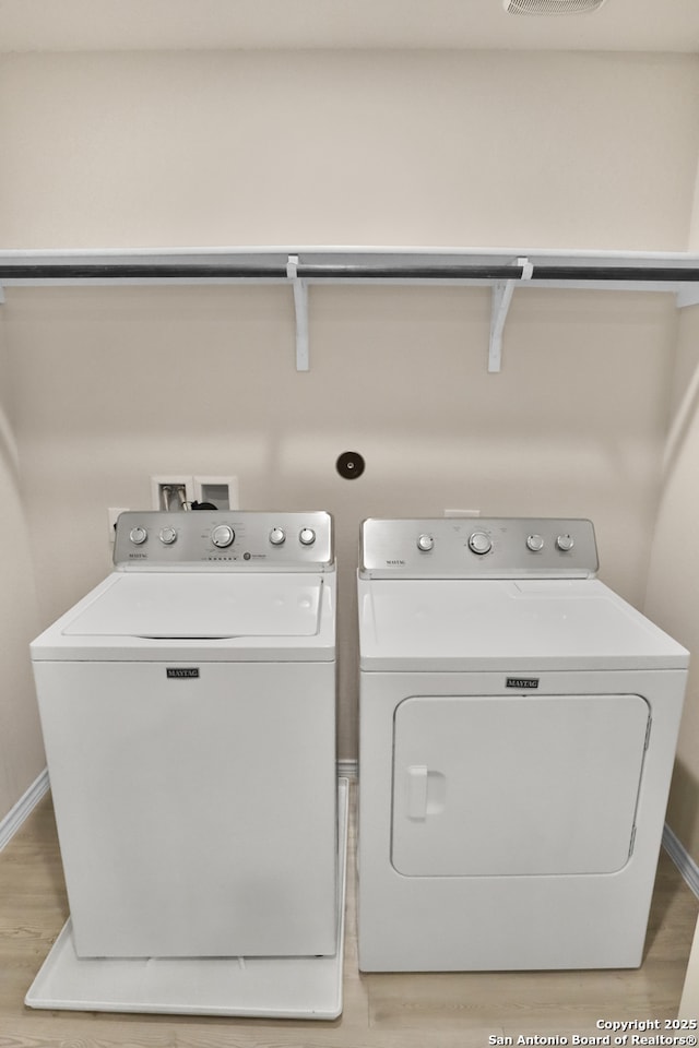 laundry room with separate washer and dryer and light hardwood / wood-style floors