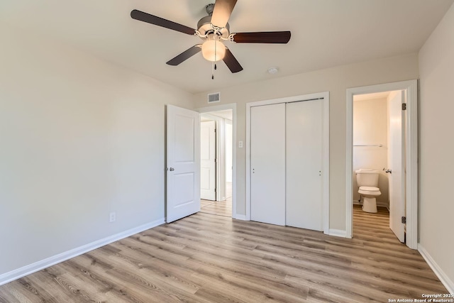 unfurnished bedroom with light wood-type flooring, connected bathroom, ceiling fan, and a closet