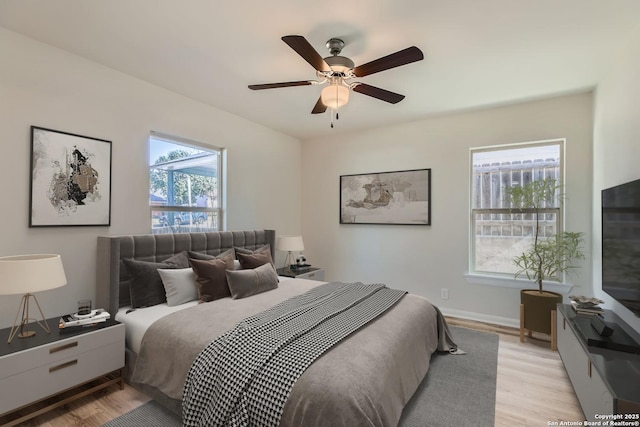 bedroom featuring multiple windows, ceiling fan, and light hardwood / wood-style flooring