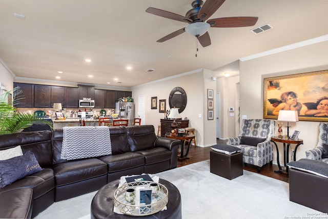 living room with hardwood / wood-style flooring, ornamental molding, and ceiling fan