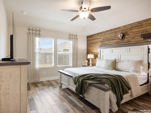 bedroom with dark wood-type flooring, ceiling fan, and wood walls