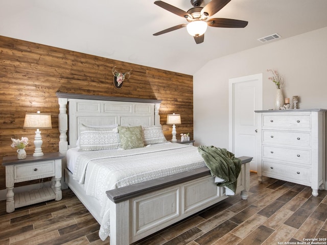 bedroom with lofted ceiling, ceiling fan, and wood walls