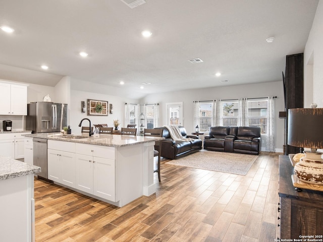 kitchen with stainless steel appliances, sink, a center island with sink, and white cabinets