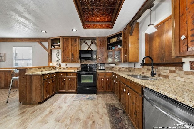 kitchen with black appliances, a kitchen breakfast bar, hanging light fixtures, kitchen peninsula, and a raised ceiling