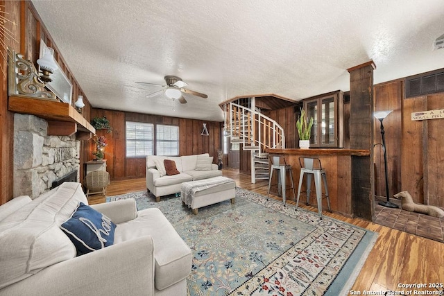 living room featuring hardwood / wood-style floors, a textured ceiling, and wood walls