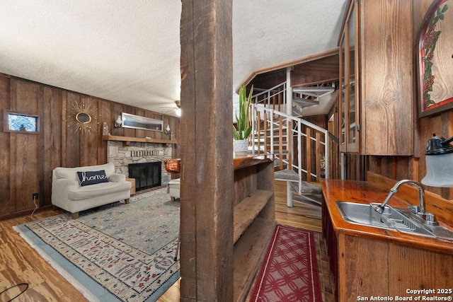 living room featuring dark wood-type flooring, sink, a fireplace, and wood walls