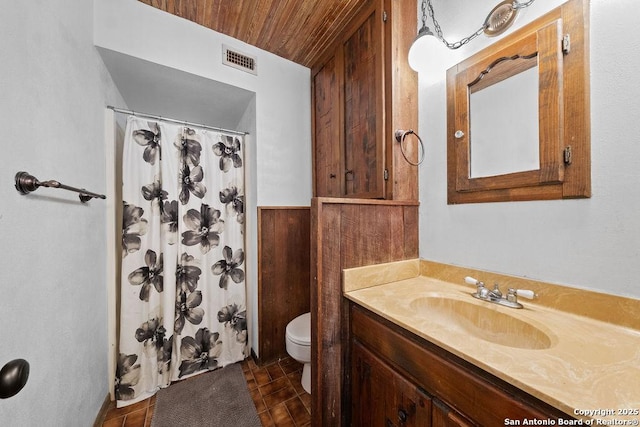 bathroom with vanity, a shower with curtain, toilet, and wood walls