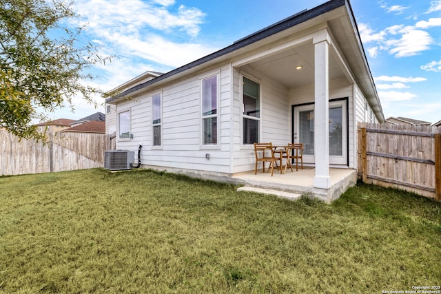 back of property with cooling unit, a yard, and a patio area