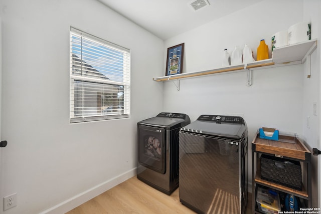 laundry room featuring separate washer and dryer and light hardwood / wood-style floors