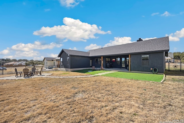 rear view of property featuring a yard and a patio area