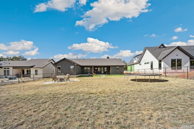 rear view of property featuring a yard and a trampoline