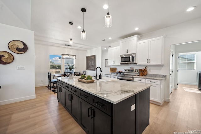 kitchen featuring sink, stainless steel appliances, an island with sink, and white cabinets