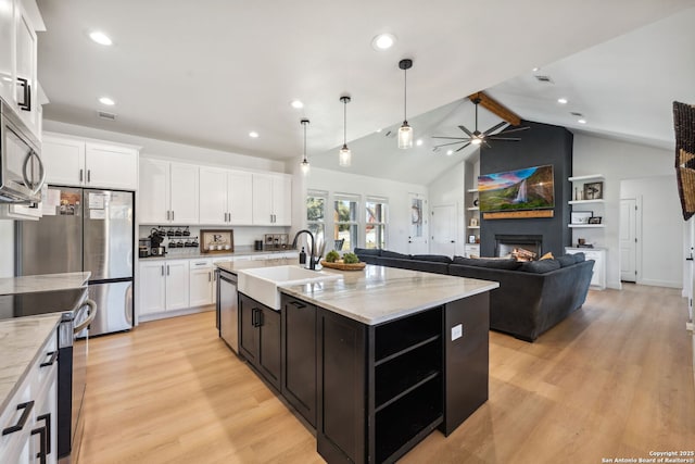 kitchen with sink, lofted ceiling with beams, an island with sink, stainless steel appliances, and white cabinets