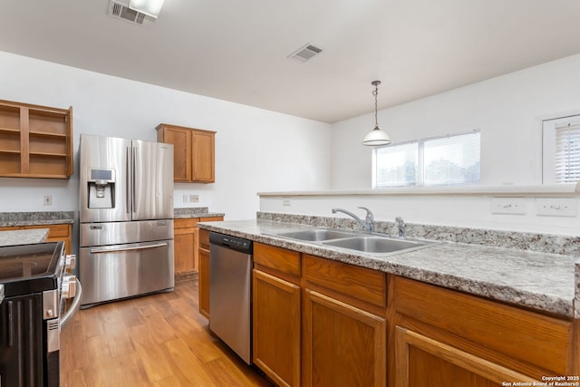 kitchen featuring sink, decorative light fixtures, light hardwood / wood-style flooring, and stainless steel appliances