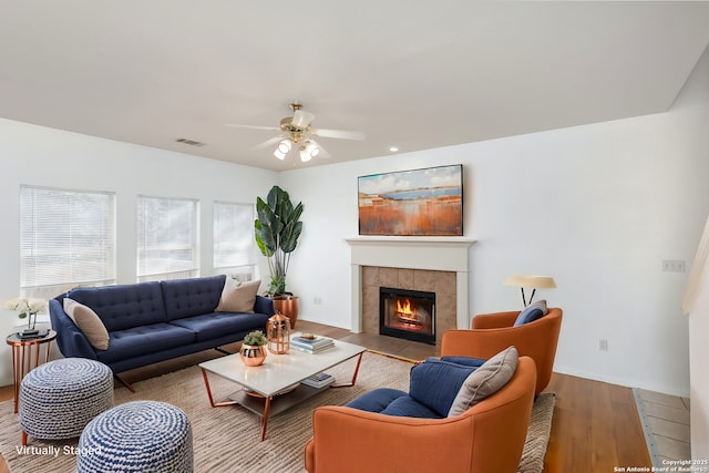 living room featuring ceiling fan, a fireplace, and light hardwood / wood-style floors