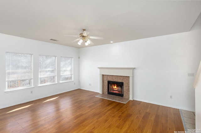 unfurnished living room with ceiling fan, hardwood / wood-style floors, and a tile fireplace