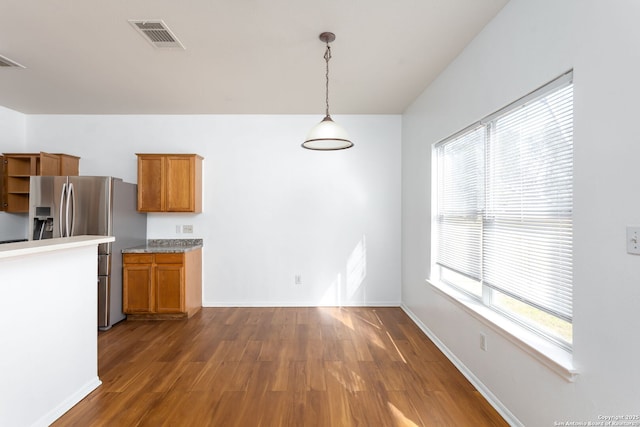 kitchen featuring stainless steel fridge with ice dispenser, hanging light fixtures, a wealth of natural light, and dark hardwood / wood-style floors