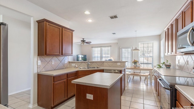 kitchen featuring sink, hanging light fixtures, electric range, light tile patterned flooring, and decorative backsplash