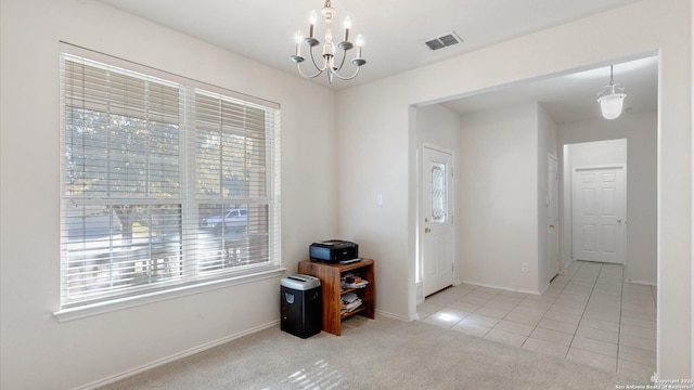 foyer entrance with light colored carpet and a chandelier